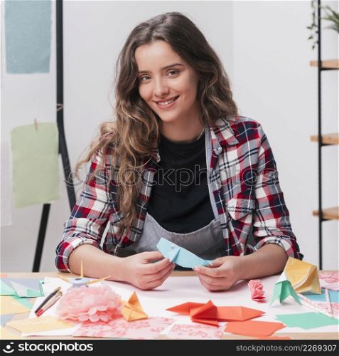 happy woman holding origami craft looking camera