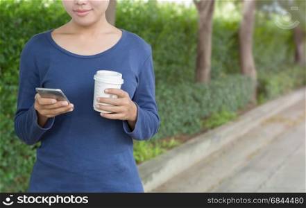 happy woman holding phone and coffee on street in fresh morning