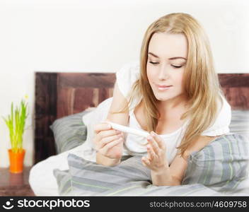 Happy woman holding pregnancy test, beautiful young female at home lying down in the bed, healthy lady checking hormone result, new life and new family concept