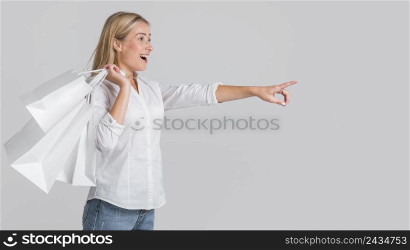 happy woman holding shopping bags pointing possible store sale