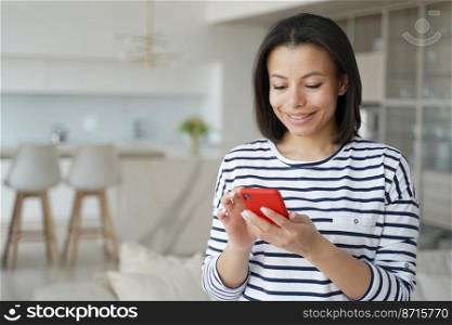 Happy woman holding smartphone, shopping on internet at home. Smiling young female communicates on social networks, makes purchases, using online services, mobile apps. E commerce concept.. Happy woman holding phone, shopping on internet, using online services, apps at home. E commerce