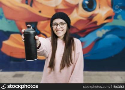 happy woman holding spray bottle front front graffiti wall