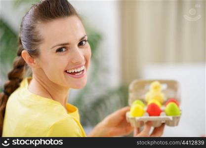 Happy woman holding tray with colorful Easter eggs