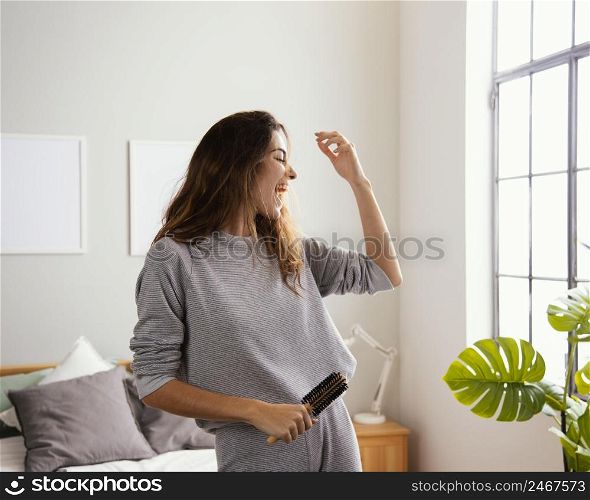 happy woman home singing while holding hairbrush