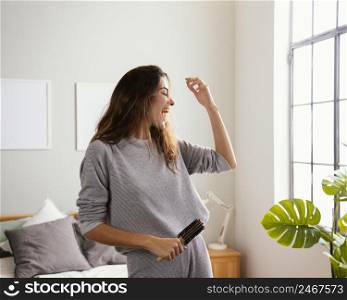 happy woman home singing while holding hairbrush