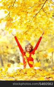 Happy woman in autumn park drop up leaves