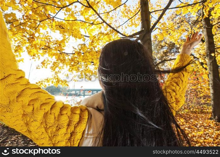 Happy woman in autumn park. Happy woman with raised hands in sunny autumn park
