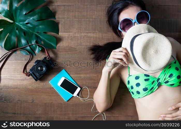 Happy woman in bikini lying down on wooden background, Beauty an. Happy woman in bikini lying down on wooden background, Beauty and Travel concept, Top view