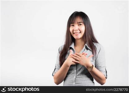 Happy woman in casual clothes holding hands at chest close to heart meditating and smiling in studio short isolated on white background, believe faith and love gratitude concept