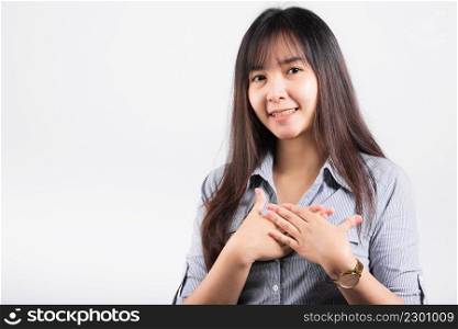 Happy woman in casual clothes holding hands at chest close to heart meditating and smiling in studio short isolated on white background, believe faith and love gratitude concept