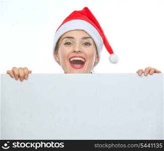 Happy woman in Christmas hat looking out from blank billboard