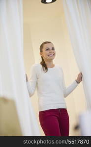 Happy woman in dressing room opening curtains
