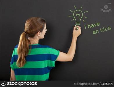 Happy woman in front of a chalkboard with a concept of having an idea design on it