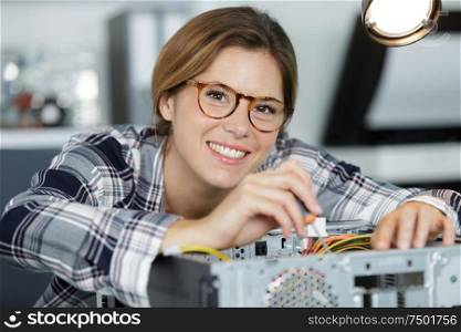 happy woman in glasses at table with broken processor