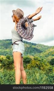 Happy woman in green field and mountain background. Freedom and travel concept.