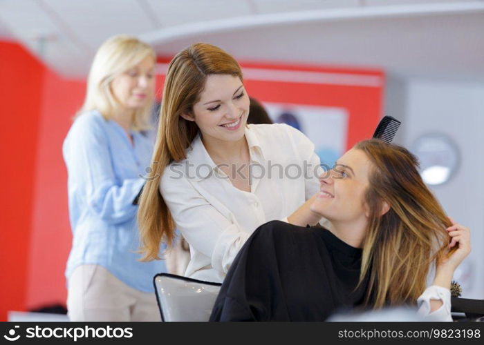 happy woman in hairdressing talking to hairdresser