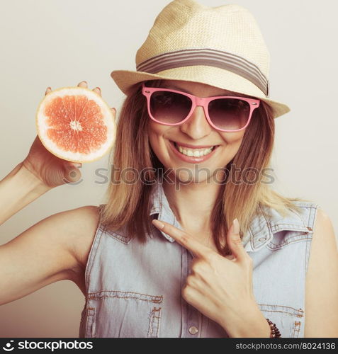 Happy woman in hat and sunglasses with grapefruit.. Happy glad woman tourist wearing straw hat and sunglasses pointing at grapefruit citrus fruit. Healthy diet food. Summer vacation holidays concept.