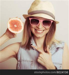 Happy woman in hat and sunglasses with grapefruit.. Happy glad woman tourist wearing straw hat and sunglasses pointing at grapefruit citrus fruit. Healthy diet food. Summer vacation holidays concept.