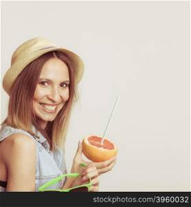 Happy woman in hat holds sunglasses and grapefruit. Happy glad woman tourist in straw hat holding sunglasses and grapefruit citrus fruit. Healthy diet food. Summer vacation holidays concept.