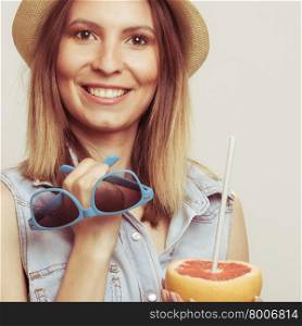 Happy woman in hat holds sunglasses and grapefruit. Happy glad woman tourist in straw hat holding sunglasses and grapefruit citrus fruit. Healthy diet food. Summer vacation holidays concept.