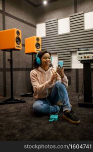 Happy woman in headphones listens to music in speaker system store. Female person in audio shop,&lifier on background, buyer in multimedia salon. Happy woman in headphones, speaker system store