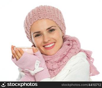 Happy woman in knit scarf, hat and mittens holding cup of tea