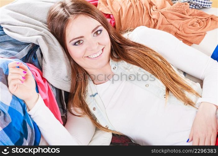 Happy woman in messy room on stack of clothes. Disorder and mess at home.. Happy woman in messy room at home.