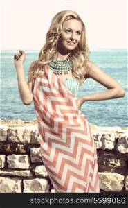 happy woman in summertime smiling and wearing pareo on bikini, turquoise big necklace and long wavy blonde hair