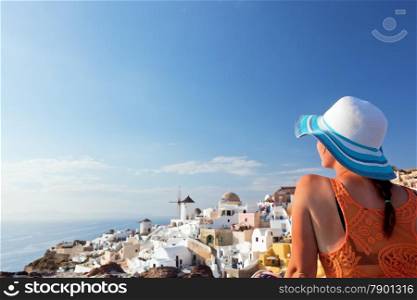 Happy woman in sun hat enjoying her holidays on Santorini island, Greece. View on Caldera and Aegean sea from Oia. Travel, tourist concepts