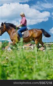 happy woman in sunglasses sitting on horse farm animal outdoors with blue sky in background