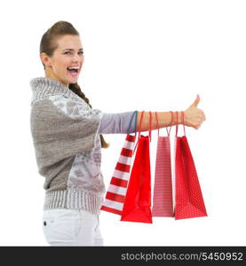 Happy woman in sweater showing thumbs up with shopping bags