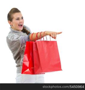 Happy woman in sweater with shopping bags pointing on copy space