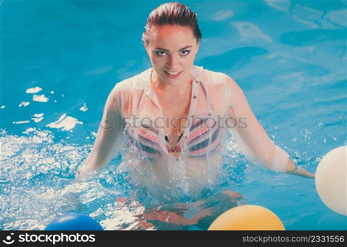 Happy woman in swimming pool water having fun with balloons. Seductive young girl wearing wet white shirt relaxing.. Happy woman in water having fun with balloons