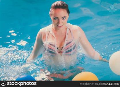 Happy woman in swimming pool water having fun with balloons. Seductive young girl wearing wet white shirt relaxing.. Happy woman in water having fun with balloons