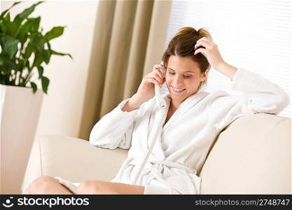 Happy woman in white bathrobe with phone home calling in lounge