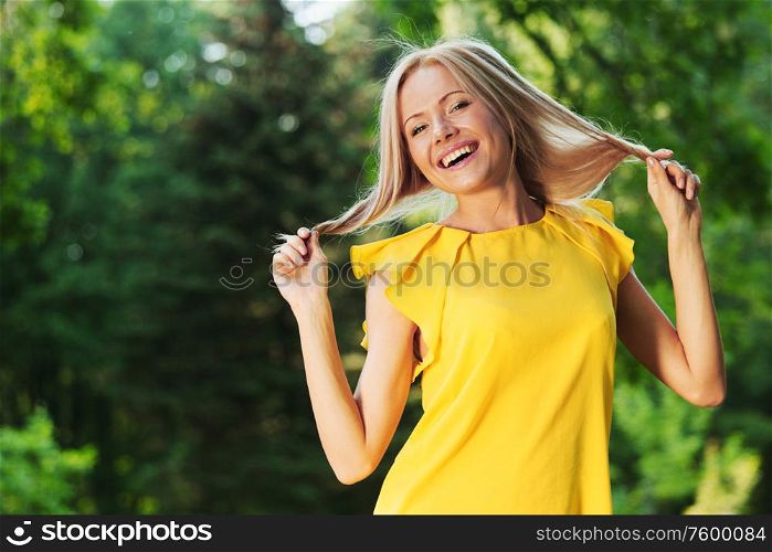 happy woman in yellow dress posing against a background of trees. happy woman in forest