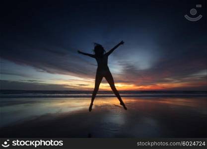 Happy woman jumping on the beach at sunset, Bali, Seminyak, Double six beach