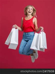happy woman jumping with lots shopping bags