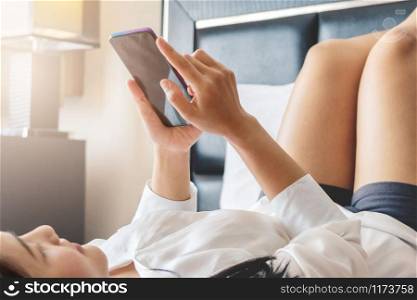 Happy woman lay on bed while surfing internet and send message on smartphone