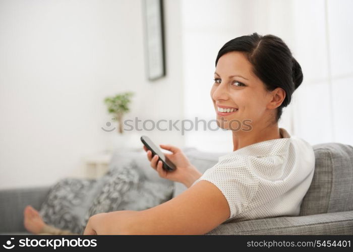 Happy woman laying on divan and holding cell phone