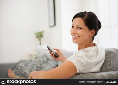 Happy woman laying on divan and holding cell phone