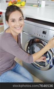 happy woman loading dirty clothes in washing machine