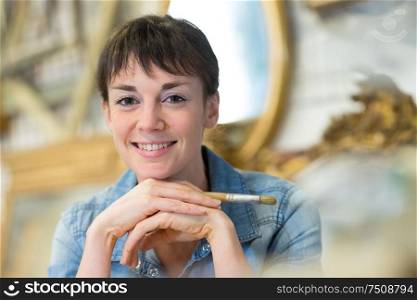 happy woman looking at camera while sitting in workshop