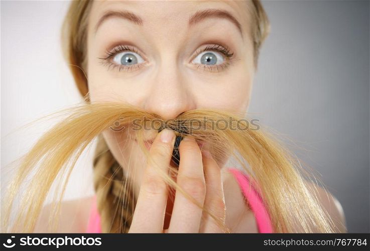 Happy woman looking at her long blonde hair ends, seeing positive effects of using conditioner. Haircare and hairstyling concept.. Happy woman looking at her hair ends