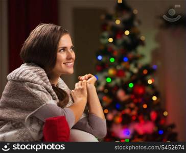Happy woman looking on copy space and Christmas tree in background