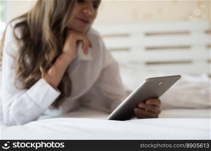 Happy woman lying on the bed with tablet computer 