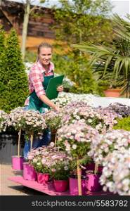 Happy woman make inventory potted flowers at garden shopping center