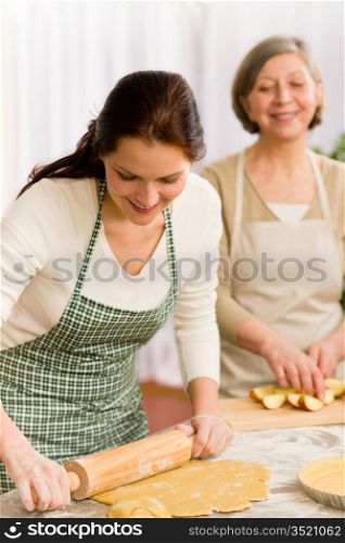 Happy woman making dough for apple pie grandmother drink wine
