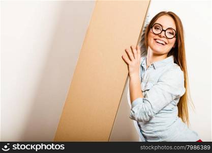 Happy woman moving into apartment carrying box.. Happy woman moving into new apartment house carrying carton box with furniture. Young girl arranging interior and unpacking.