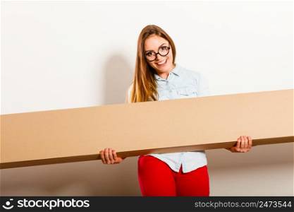 Happy woman moving into new apartment house carrying carton box with furniture. Young girl arranging interior and unpacking.. Happy woman moving into apartment carrying box.